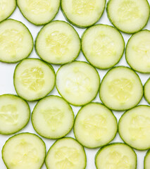 Background created from green ripe natural organic cucumber sliced into circles on white background