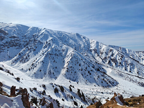 Snow-covered mountain landscape with rugged terrain and clear blue sky in the background