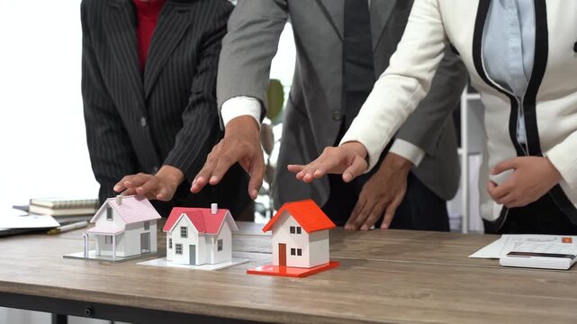 Negotiation in Property: Professionals, arrayed on a table with miniature property models, engage in a focused negotiation over real estate, as if making important decisions that will shape futures.