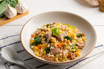 Tuna fried rice,stir fry rice with canned tuna fish ,kale ,corn ,carrot ,green peas and egg in white plate.