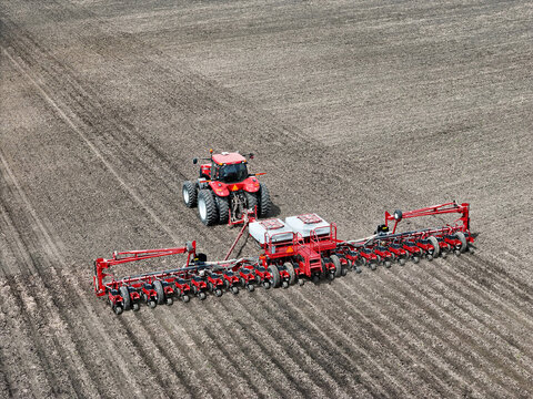Red tractor pulling a red Vacuum Hydraulic Drive 24 row planter