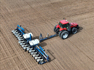 Aerial view of a red tractor pulling a blue 16 row planter