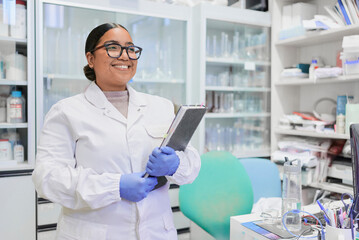 Latina woman in lab coat and blue gloves holding a scientific notebook in her research lab