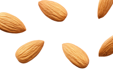 almonds are falling in the air on a white surface
