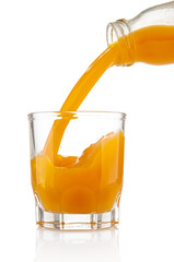 Pouring orange juice in tumbler glass from bottle on white background