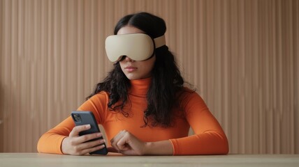 A woman in an orange turtleneck uses a smartphone while wearing a beige VR headset against a wooden backdrop.