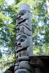Intricate Indigenous Totem Pole Against a Forest Backdrop