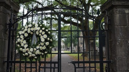 White funeral wreath hanging on cemetery gate