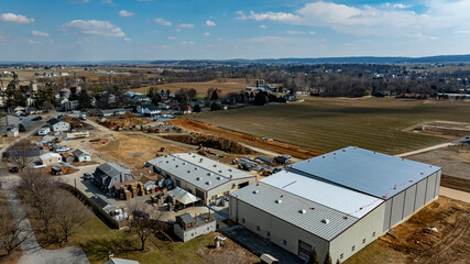 In a developing rural area, a large warehouse is under construction next to small houses and...