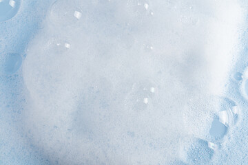 Lots of beautiful clear soap bubbles on the white surface of the detergent. white soapy texture. blue water surface. layout to advertise your product.