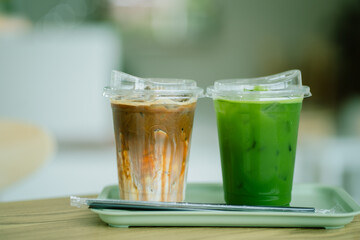 Close up glass of ice caramel macchiato and ice pure matcha green tea on green tray of a coffee shop summer terrace, menu photography.