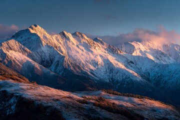 Obraz premium At dawn, the suns first light graces the snow-covered peaks of a majestic mountain range. The scene captures a breathtaking view where golden hues meet pristine white snow