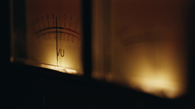 Analog meter measuring audio signal inside retro studio macro view. Glowing VU