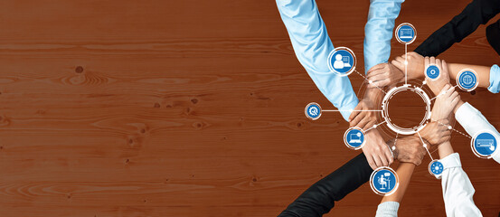 A diverse group of hands joins together, symbolizing teamwork and collaboration, with technology...