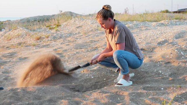 white girl squatting digging hole with sapper shovel in desert. Close up