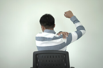 Man having tensed muscles fatigued, neck, shoulder, back, wrist and arm pain during work long time in office, due to fibromyalgia, rheumatism, scapular pain, office syndrome and ergonomic concept.