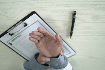 Man having tensed muscles fatigued, neck, shoulder, back, wrist and arm pain during work long time in office, due to fibromyalgia, rheumatism, scapular pain, office syndrome and ergonomic concept.