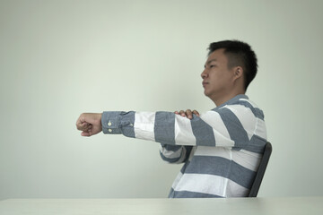 Man having tensed muscles fatigued, neck, shoulder, back, wrist and arm pain during work long time in office, due to fibromyalgia, rheumatism, scapular pain, office syndrome and ergonomic concept.