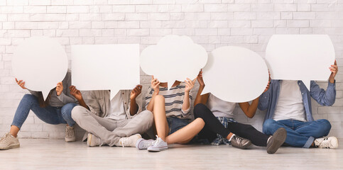 Young people in casual clothes hiding behind speech bubbles, sitting on floor, communication...