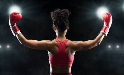 Back view of afro woman boxer champion celebrating win over stadium background, panorama
