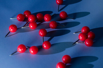 Bright red pushpins scattered on a cool blue background evoke focus, urgency, and creative planning...