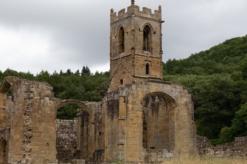 Obraz premium Medieval tower anchors crumbled abbey; arched windows and mossy stone evoke sacred echoes beneath soft gray skies in Mount Grace Priory - East Harlsey - North Yorkshire - UK