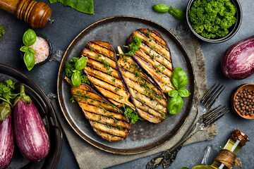 Juicy baked eggplants. Grilled vegetables. On a gray concrete background.