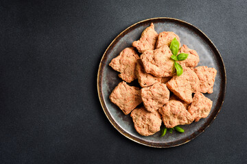 Dry vegan meat. Soy meat in a plate. On a black textured background. Top view.