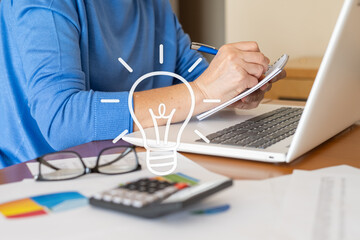 Businesswoman having new ideas and taking notes while working at her desk with a laptop and...