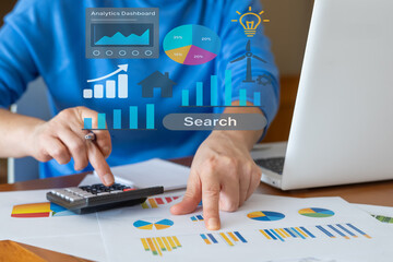 Businessman using a calculator and pointing at financial charts, analyzing data with a digital...