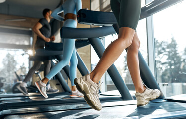 Close-up of active legs running on treadmills in gym