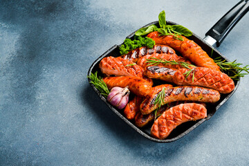 A set of pork, beef and chicken sausages in a metal grill pan. Top view, free space for text.