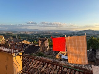 Sunset over an old Italian town. A balcony with fresh laundry hanging, overlooking tiled rooftops...