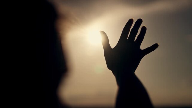 Hand extended seeking help in sunlight. Light shining through fingers, symbolizing help and hope. Arm reaching towards light in hopeful gesture. Helping hand in sunlight. Arm extended for help light.