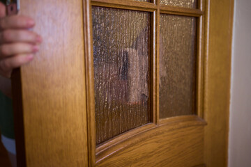 Obraz premium Carefully Hand Cleaning a Sparkling Glass Door with a Soft Sponge in the Kitchen Area