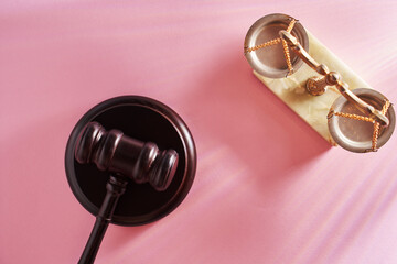 top view of gavel hammer and libra scale against pink background