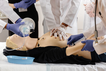 Doctors practicing cardiopulmonary resuscitation and intravenous injection on medical manikin