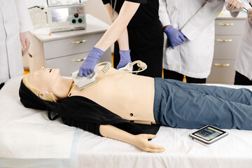 Paramedics practicing defibrillation on a medical manikin during first aid training