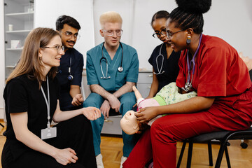 Medical students practicing infant care on a medical manikin