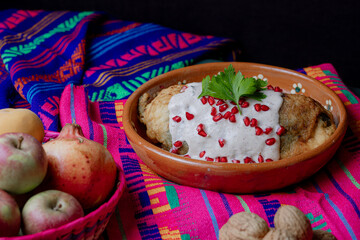 Classic Mexican chile en nogada served in a clay dish with fresh ingredients: apple, pear, walnut,...