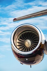 Detailed close-up of a jet engine intake from a low vertical angle. The image showcases the turbine blades, shiny nacelle, and part of the tail structure above.  © Paul