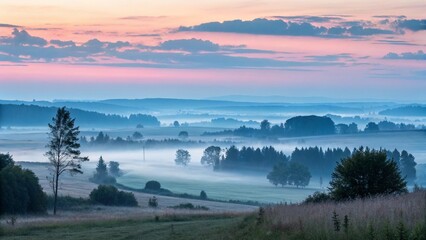 Fototapeta premium Misty rolling hills at sunrise with pink and blue sky
