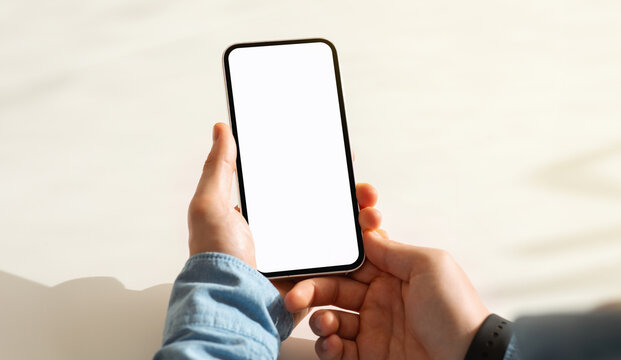 Millennial caucasian guy hand hold mobile phone with blank screen, work, study or online communication in cafe, cropped, pov. Website, blog and app recommendation, close up