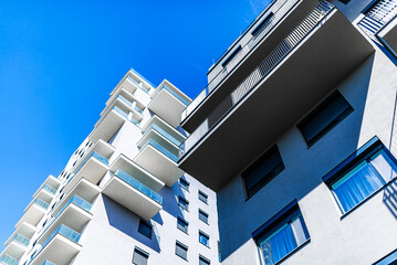 Modern Multi-Story Residential Building with Vibrant Facade, Large Balconies, and Scenic Urban Skyline under Clear Blue Sky