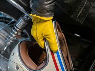 close up of biker in yellow leather gloves holding white helmet
