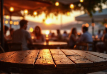 Empty rustic wooden table with copy space in pub. Background of blurred people sitting outdoor at sunset,  warm, moody atmosphere. Summer and vacation vibes.