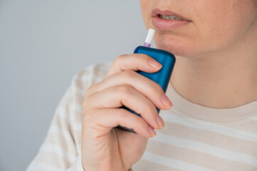Caucasian woman smoking electronic cigarette. Tobacco heating system.