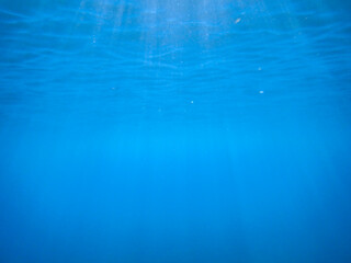 Tropical blue ocean with white bubbles underwater in Mediterranean Sea. Ocean background, underwater blue ocean background with sandy sea bottom, Blue deep water abstract natural bubble background.