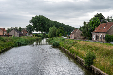 Fototapeta premium Residential houses at the green banks of the canal in Zomergem, East Flanders, Belgium