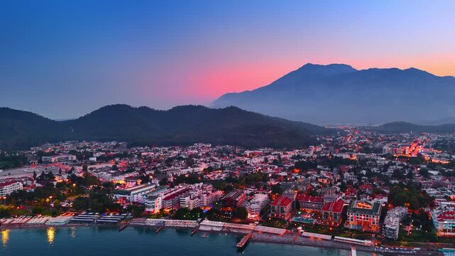 Approaching colorful cityscape of the modern resort in Fethiye, Turkey at sunset. Pink sky behind the mountains in the backdrop.
